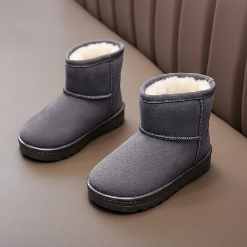 Pair of gray suede snow boots with white fur lining on a brown surface.